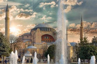 fountain in front of brown concrete building under cloudy sky during daytime