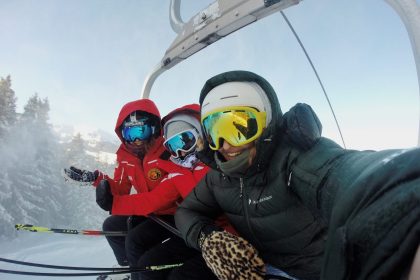 three person wearing ski gear riding cable car