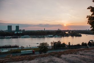 body of water near city buildings during sunset