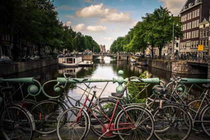 assorted-color bicycles park beside blue rails near river