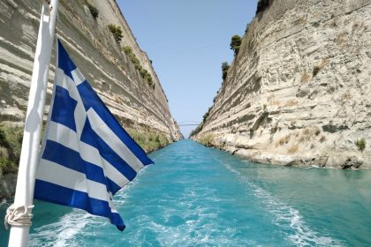 blue and white striped flag on rock formation near body of water during daytime