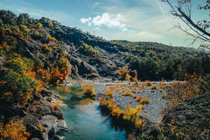 green and brown mountains beside river under blue sky during daytime