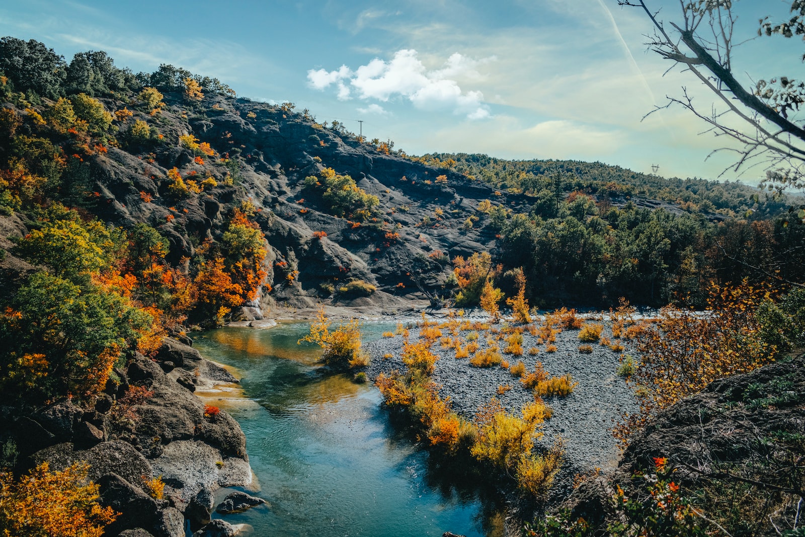 green and brown mountains beside river under blue sky during daytime