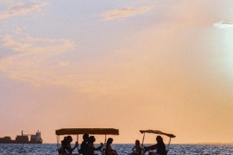 people riding on a boat on a lake during sunset