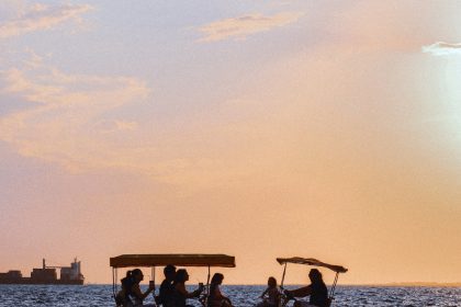 people riding on a boat on a lake during sunset