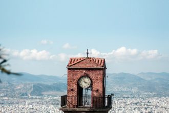 a clock tower on top of a building with a city in the background