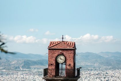 a clock tower on top of a building with a city in the background
