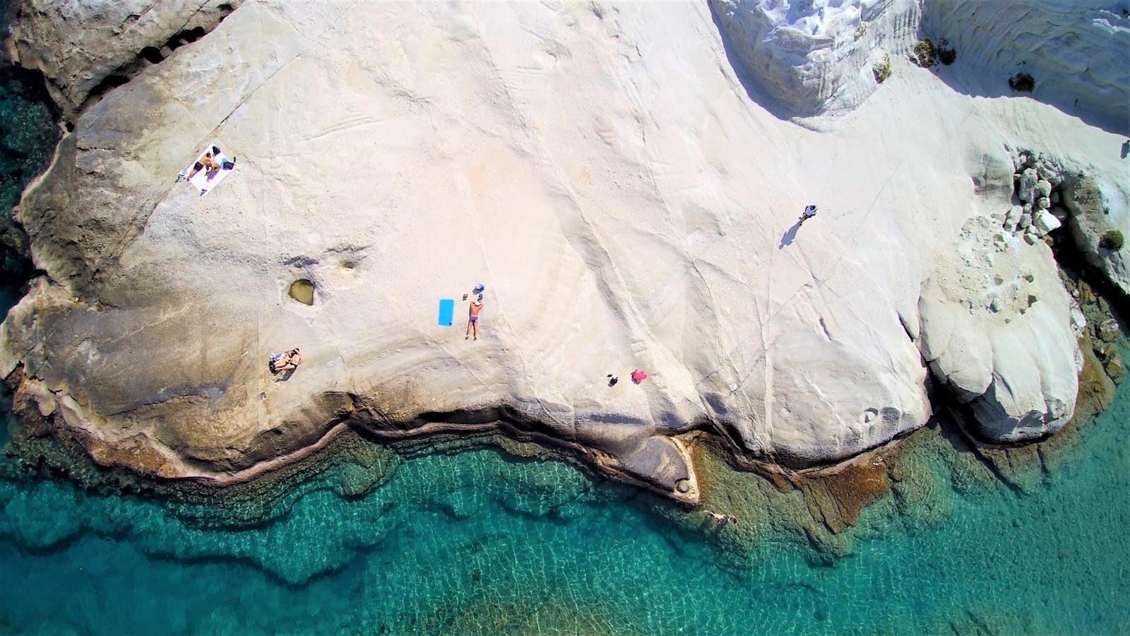 Aerial View of People on Rocky Island Along a Body of Water