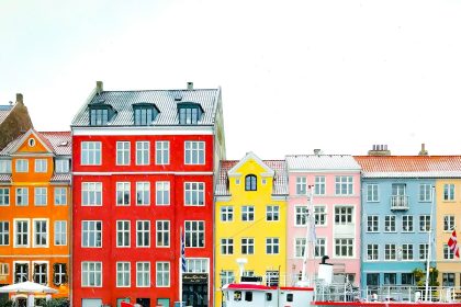 assorted-color buildings near red boat docked on port during daytime