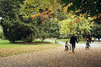 A family enjoys a bike ride through a scenic park in Nancy during fall.