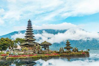 brown and green temple near body of water under blue and white cloudy sky during daytime