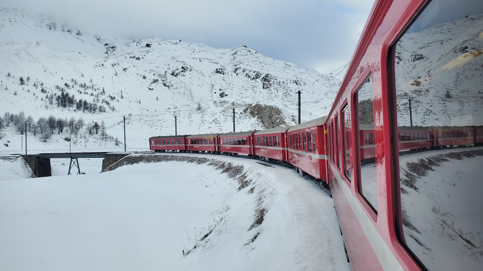 a red train traveling down train tracks next to a snow covered mountain