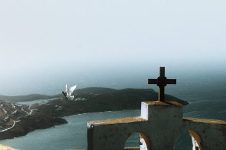 a cross on top of a building overlooking a body of water