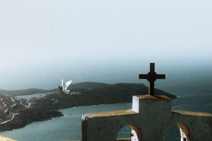 a cross on top of a building overlooking a body of water